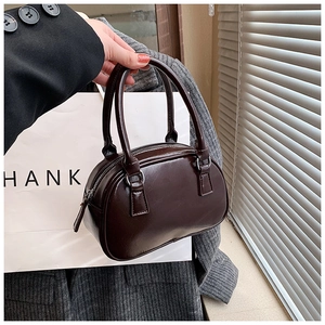 Detail of dark brown glossy patent leather boston handbag with silver metal buckles