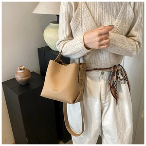 Chic beige lychee leather bucket bag styled with a neutral outfit and silk scarf detail