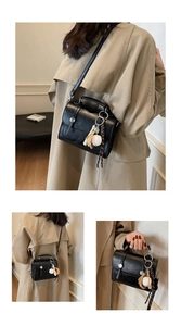 Detail of black pebbled leather satchel with baseball charms and silver metal lock