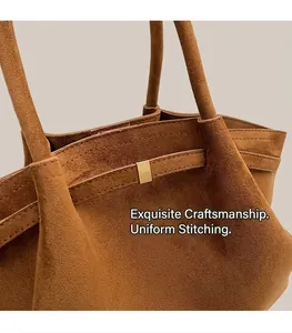 Gros plan d'un sac cabas en daim marron avec coutures fines et boucle en métal doré