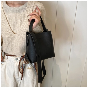 Detail of black lychee grain leather bucket bag with top handle and wide strap