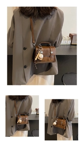 Close-up of vintage brown leather satchel featuring unique baseball themed charms
