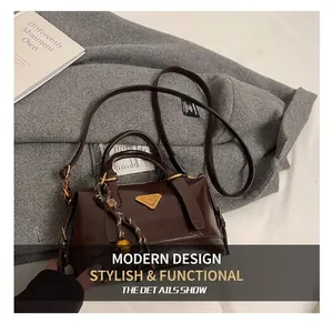 Detailed close-up of dark brown leather handbag with metallic triangle logo and woven charm
