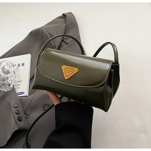 Close-up of olive green patent leather bag featuring a gold triangle logo plaque