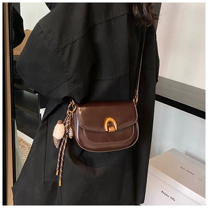 Nahaufnahme der braunen Vintage-Satteltasche mit goldener Schnalle und Plüschanhänger