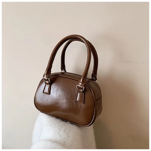 Macro shot of dark brown glossy faux leather texture and stitching on the boston bag