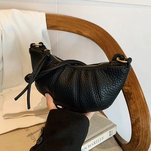 Chic black lychee grain croissant bag with elegant gold ring and leather tassel detail