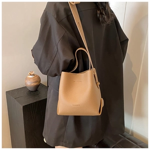 Detailed view of brown litchi grain leather bucket bag with wide shoulder strap