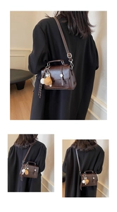 Detailed view of brown vintage square bag with baseball charm on black blazer
