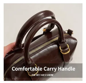 Detail of dark brown glossy leather handbag with golden metal zipper and round handles