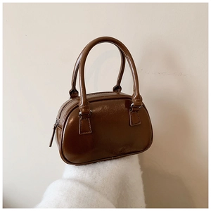 Detail of a glossy brown bowling bag with double top handles and metallic hardware details
