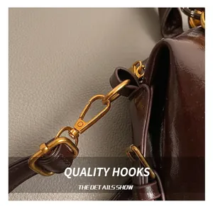 Close-up of premium gold-tone metal hook and stitching on dark brown leather handbag