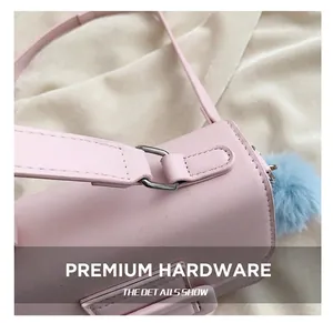 Dettaglio borsa a tracolla in pelle rosa con fibbie argentate e ciondolo a pompon blu