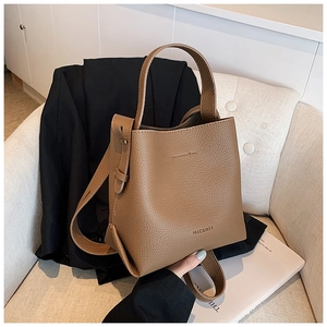 Close-up of brown lychee grain leather bucket bag with top handle on armchair