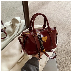 Detailed macro of vintage dark red Boston bag with gold hardware and woven rope charms