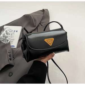 Detail of a vintage black oil wax leather pillow bag with gold triangular metal logo