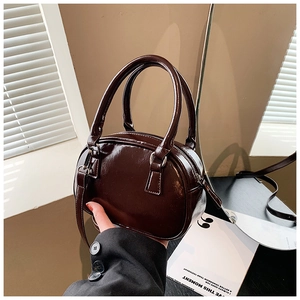 Macro detail of glossy chocolate brown patent leather handbag with silver metal zippers