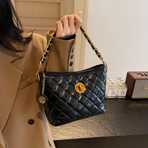 Classic black quilted shoulder bag with gold twist lock and chain strap on a model