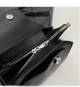 Detail of lychee textured leather crossbody bag showing silver zipper and magnetic buckle