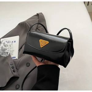 Close-up of vintage black oil wax leather pillow bag with yellow triangular metal logo