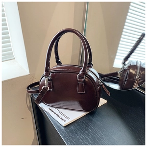 Detail of a deep brown bowling bag in glossy patent leather with silver hardware