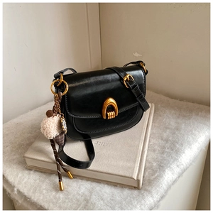 Detail der schwarzen Satteltasche mit goldenem Hufeisenverschluss und Plüschanhänger