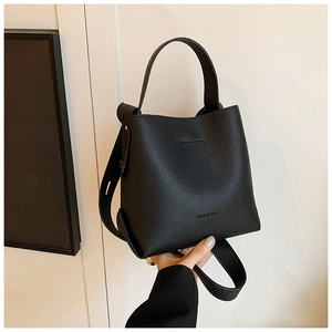 Detail of black lychee grain leather bucket bag featuring a sturdy handle and wide strap