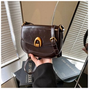 Detail einer dunkelbraunen Satteltasche mit goldener U-Schnalle und stilvollem Retro-Design