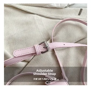 Dettaglio della tracolla regolabile in pelle rosa con fibbia argentata su tessuto in tweed