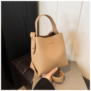 Detail showing the litchi grain texture and MACGNEE branding on the beige bucket bag