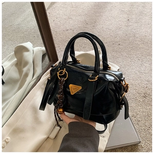 Detail of glossy black Boston bag with golden triangle hardware and leather texture