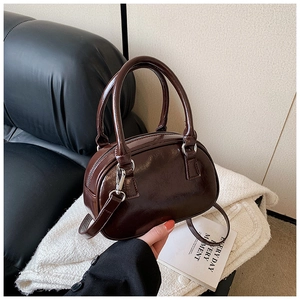 Detailed view of glossy dark brown bowling bag with silver zipper and slim strap