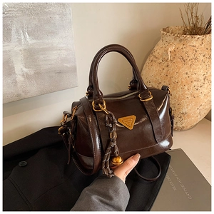 Detail of dark brown polished leather bowling bag with vintage triangle metal plaque