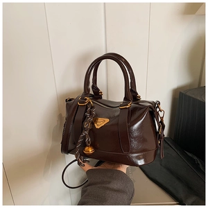 Detailed close-up of dark brown wax leather bag with triangle logo and tassel zipper