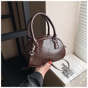 Detailed shot of dark brown glossy leather handbag with silver hardware and adjustable strap