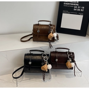 Close-up of three vintage mini crossbody bags in black, dark brown, and caramel colors