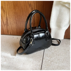 Detail of glossy black bowling bag with silver hardware and smooth leather texture