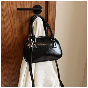 Close-up of a glossy black mini bowling bag hanging with elegant silver hardware details