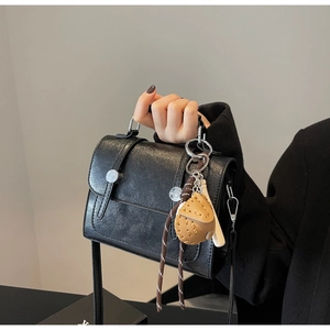 Detailed close-up of retro black crossbody bag with leather baseball glove charm