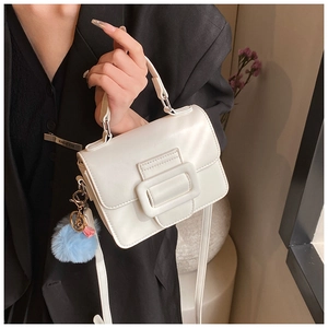 Dettaglio della borsa mini a tracolla bianco crema con fibbia quadrata e charm blu