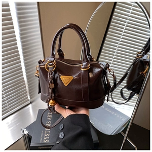 Close-up of dark brown leather Boston bag featuring gold hardware and logo plaque