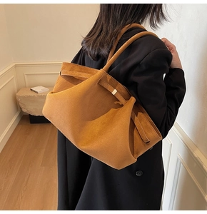 Détail du grand cabas en daim marron avec texture mate et boucle métallique latérale