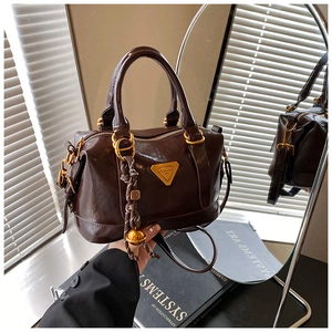 Detail of dark brown oil wax leather Boston bag with golden triangle logo and tassel