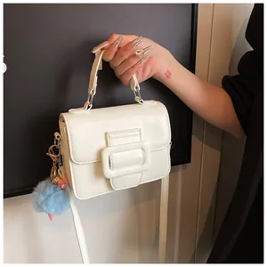 Borsa a tracolla quadrata in pelle bianca con pompon blu e ciondolo con nappine rosa