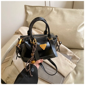 Detail of black glossy Boston handbag featuring gold hardware and triangle logo accent