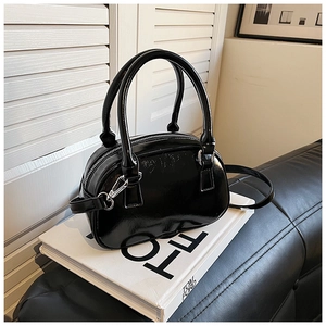 Detailed view of black patent leather mini bowling bag with glossy finish and silver zippers