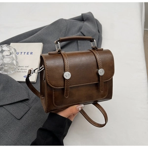 Detail of vintage brown leather handbag with silver buckles and elegant round handle
