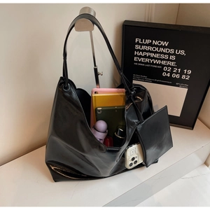 Detail of black glossy leather tote bag showing large capacity for laptop and daily items