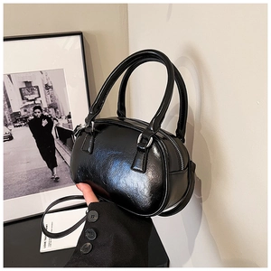 Detail of glossy black pillow handbag with silver hardware and leather texture