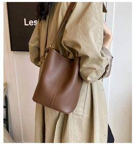Gros plan sur un sac seau en cuir marron à motif litchi avec des finitions dorées